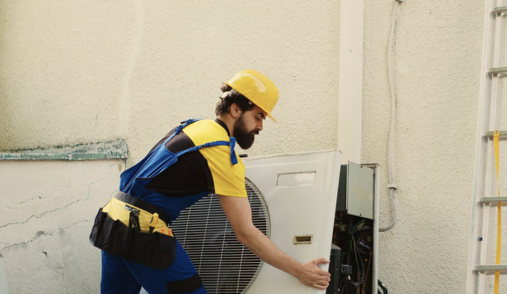 An HVAC technician servicing an outdoor air conditioning unit.